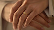 Two hands with wedding and engagement rings gently touch, symbolizing union.