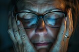 Fototapeta Londyn - Exhausted woman taking off her glasses, her fingertips gently massaging her closed eyelids. Common issue of eyestrain and the need for rest and relief.