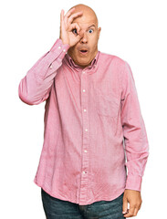 Wall Mural - Middle age bald man wearing casual clothes doing ok gesture shocked with surprised face, eye looking through fingers. unbelieving expression.