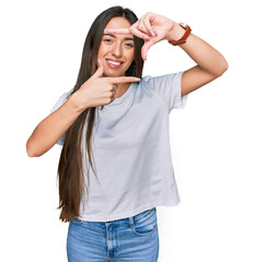 Canvas Print - Young hispanic girl wearing casual white t shirt smiling making frame with hands and fingers with happy face. creativity and photography concept.