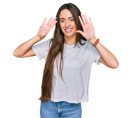 Sticker - Young hispanic girl wearing casual white t shirt showing and pointing up with fingers number nine while smiling confident and happy.