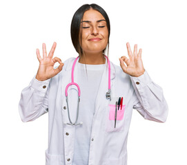 Wall Mural - Beautiful hispanic woman wearing doctor uniform and stethoscope relax and smiling with eyes closed doing meditation gesture with fingers. yoga concept.