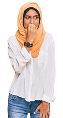 Sticker - Young brunette woman wearing traditional islamic hijab scarf looking stressed and nervous with hands on mouth biting nails. anxiety problem.