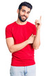 © Krakenimages.com - Young handsome man with beard wearing casual t-shirt with a big smile on face, pointing with hand and finger to the side looking at the camera.