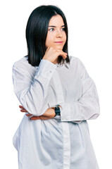 Poster - Young brunette woman with blue eyes wearing oversize white shirt with hand on chin thinking about question, pensive expression. smiling and thoughtful face. doubt concept.