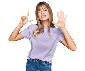 Wall Mural - Teenager caucasian girl wearing casual clothes showing and pointing up with fingers number seven while smiling confident and happy.