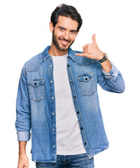 Wall Mural - Young hispanic man wearing casual clothes smiling doing phone gesture with hand and fingers like talking on the telephone. communicating concepts.