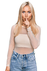 Wall Mural - Young blonde woman wearing casual clothes asking to be quiet with finger on lips. silence and secret concept.