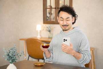 Wall Mural - Asian (Japanese) man looking at his phone with coffee in a fashionable cafe