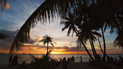 Wall Mural - silhouetted people and palms near sea. sunset at tropical white beach, boracay island, philippines, 