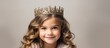 The little girl, with her blond hair and sparkling eyelashes, wears a crown as a fashion accessory on her headpiece. She smiles happily at the event