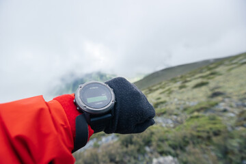 Wall Mural - Hiker on high altitude mountain top checking the altimeter on the sports watch