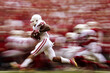 © weerasak - A dynamic action shot of a college football game, capturing a pivotal play with blurred motion, leaving room in the foreground for insights on the game's outcome or player achievements