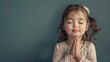 cute little girl praying with folded hands and closed eyes - studio portrait with copyspace