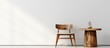 Simple wooden chair and table placed in a clean white room with a matching white wall, creating a minimalist and serene ambiance
