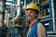 © Nataliia_Trushchenko - A woman wearing a blue vest and a orange helmet. Portrait of happy female engineer at oil refinery, woman engineer inspecting in industrial oil refinery wearing construction helmet and blue vest