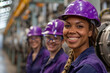 © Nataliia_Trushchenko - A group of women wearing safety gear and smiling for the camera. Scene is positive and cheerful. several smiling teamwork of woman wearing purple hard hats stand on the factory