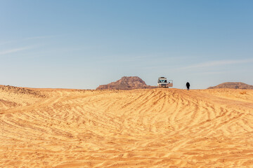 Wall Mural - Bedouin walks next to the white car in the Sinai desert. Egypt.