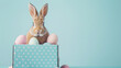 Charming Easter Bunny Sitting in a Polka-Dotted Gift Box Surrounded by Pastel Eggs, Perfect for a Holiday Celebration Greeting Card Isolated on a Soft Blue Background