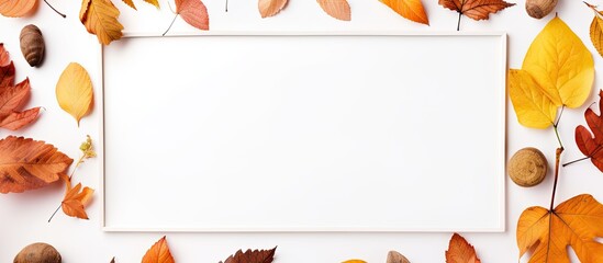 Wall Mural - A white frame surrounded by vibrant autumn leaves and various nuts in a seasonal composition