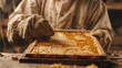 Close-up of a beekeeper's gloved hands carefully inspecting a honeycomb frame covered in bees amidst a warm lit workshop.