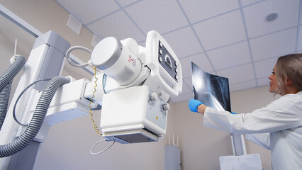 Wall Mural - Doctor with x-ray of lungs in hands in modern medical radiology hospital. The doctor analyzes the condition of the lungs. COVID-19 and medical examinations.