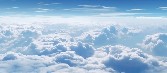 Wall Mural - Numerous fluffy clouds are scattered across the blue sky, high above the Earth's surface, creating a picturesque scene