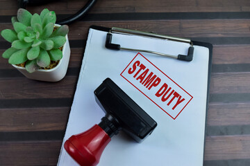 Red Handle Rubber Stamper and Stamp Duty text above paperwork isolated on wooden background