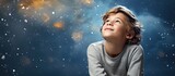 Fototapeta  - A young kid with curious eyes staring up at the vast blue sky above in wonder and amazement