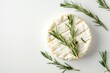 Camembert cheese with sprigs of rosemary on a white isolated background