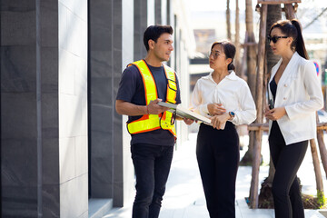 business woman and Office building owner and energy engineer plan a project to build a solar panel for the building under construction. clean and green alternative energy concept