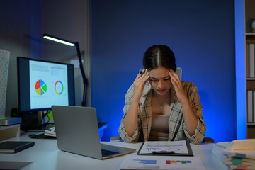 Poster - A woman is sitting at a desk with a laptop and a stack of papers