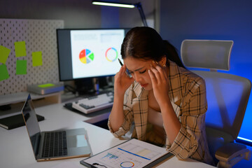 Poster - A woman is sitting at a desk with a laptop and a stack of papers
