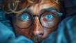 A man with glasses and blue eyes is looking at the camera. The image has a moody feel to it, as the man is partially hidden by a blanket. looking curious and intressted, eager to know the answer