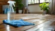 A bottle of cleaning solution sits on a blue cloth on a wooden floor
