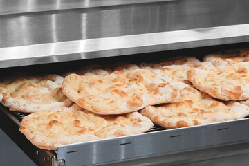 Poster - Fresh fragrant flatbread bread on a metal table in a bakery. Nutrition concept