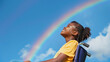 Happy disabled black afro american girl in wheelchair looking at rainbow in sky. Inclusion diversity & disability representation. Gay pride festival concept with rainbow. Acceptance & hope. Copy space