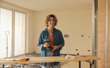 Fototapeta Panele - Woman holding a drill gun while renovating her home's kitchen