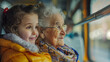 A senior woman and her young granddaughter are seated together on a bus on a joint excursion