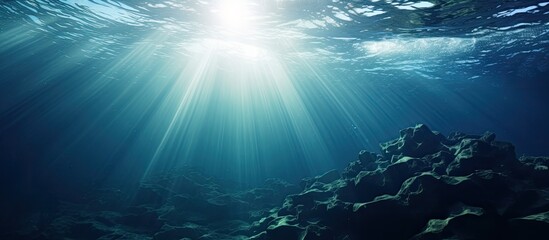 Wall Mural - The sunlight is shining through the water in the ocean, creating a beautiful natural landscape with the sky and sun above and the underwater world below