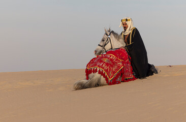 Wall Mural - Saudi Man with his white stallion in a desert