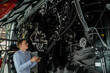 © scharfsinn86 - Serviceman with digital tablet next to combine harvester with open hood