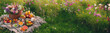 Banner romantisches natürliches Land Leben Liebe Essen Picknick in der freien Natur auf Wiese voller Blüten auf Decke im Gras mit Früchten Brot Wein Korb voller Lebensmittel Bäume warm sommerlich 