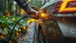 Hand inserting EV charging plug to electric vehicle in focus shot with blurred background of outdoor natural greenery