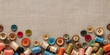 Colorful spools of thread and buttons on beige linen fabric background, copy space. Handicraft concept