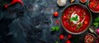 Banner with space for text. Borscht with greens and garlic in clay bowl on dark stone background. Beet soup top view. Food photo for menu, restaurant, catalog, advertisement. Plate of red beet soup