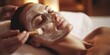 Peeling facial mask, spa treatments, skin care. Woman receiving facial treatment from cosmetologist in spa salon, close-up
