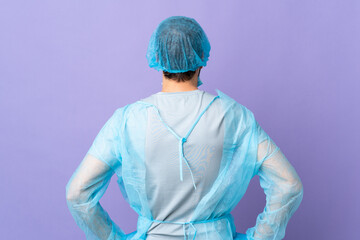 Wall Mural - Surgeon man with beard with blue uniform over isolated purple background in back position