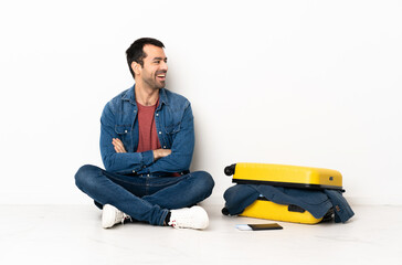 Wall Mural - Caucasian handsome man with a suitcase full of clothes sitting on the floor at indoors happy and smiling