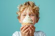 Child boy holding sweet cupcake with whipped cream on blue background